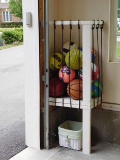 basketballs and balls are stored in the corner of a room with an open door