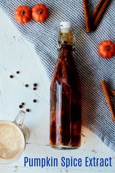 a bottle of pumpkin spice extra next to cinnamon sticks and an apple cider on a towel