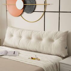 a bed with a book on top of it next to a wall mounted art piece