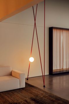 a white couch sitting on top of a wooden floor next to a lamp and window