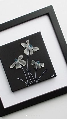 a black and white frame with some flowers on the inside is holding an image of three petals