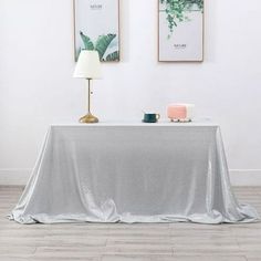 a table with a silver cloth on it in front of two pictures hanging on the wall