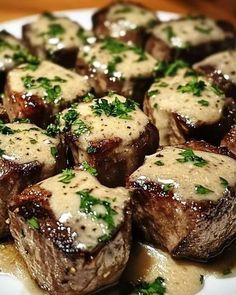 a white plate topped with meat covered in gravy and garnished with parsley