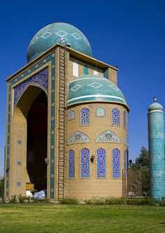 a large building with blue and green tiles on it's sides, in the middle of a grassy area