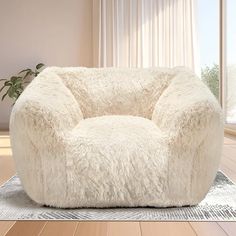 a large white chair sitting on top of a wooden floor next to a potted plant