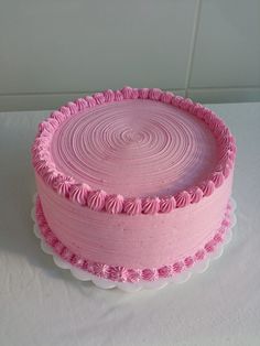 a pink cake sitting on top of a white table