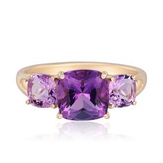 three stone ring in yellow gold with purple stones