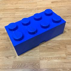 a blue lego block sitting on top of a wooden floor