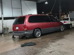 a red van parked in front of a building with another car behind it on the street