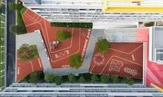 an aerial view of a tennis court in the middle of a city with trees and buildings