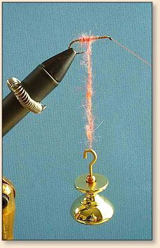 a gold colored hook with a black handle and red thread attached to it, sitting next to a fountain pen