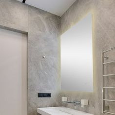 a white sink sitting under a large mirror next to a wall mounted towel dispenser