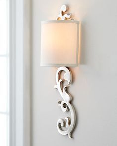 a white lamp mounted on the side of a wall next to a light fixture in a room