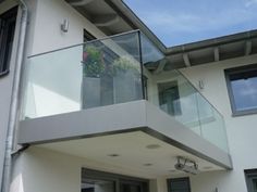 a white house with a balcony and glass balconies on the top floor is shown