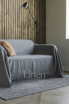 a gray couch sitting on top of a hard wood floor next to a lamp and window