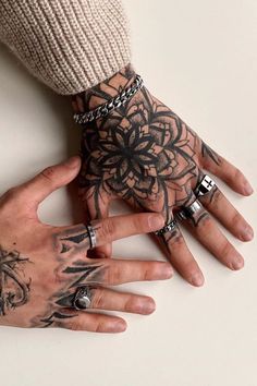 two hands with tattoos and rings on them