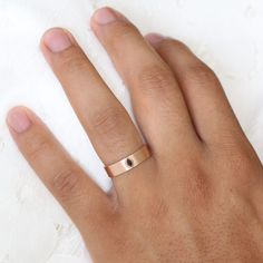 a person's hand with a gold ring on top of their left hand and a white towel in the background