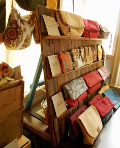 a shelf with many bags and purses hanging from it's sides in front of a window