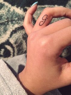 a person's hand with a small tattoo on their left thumb and the letter c in the middle