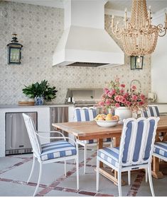 a dining room table with blue and white striped chairs next to a stove top oven