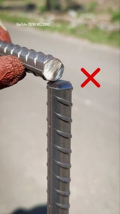 a close up of a person's hand holding a metal object with a red cross on it