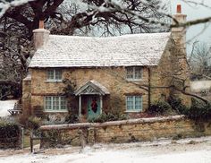 an old stone house with a wreath on the front door and chimneys is covered in snow