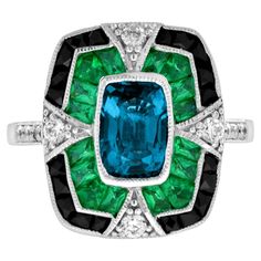 A striking and intriguing jewel, indeed. This bold and colorful Art Deco style ring highlights a gorgeous gleaming emerald cut London blue topaz framed in eye-catching contrast by French cut emerald and black onyx. Each side and shoulders set off with round diamond with milgrain edge. Ring Information Style: Edwardian Metal: 18K White Gold Weight: 6.50 g. (approx. total weight) Ring Size: US3-8 Center Gemstone Type: London Blue Topaz Shape: Octagon Size: 8 x 5.5 mm. Number: 1 Weight: 2.00 Carat Luxury Blue Art Deco Rings, Vintage Emerald Rings Blue Nile, Luxury Enamel Art Deco Rings, Gem Rings Stones 1stdibs, Edwardian Onyx Rings, Luxury Emerald Gemstones With Accent Stones, Luxury Multi-stone Emerald Cut Emerald Ring, Art Deco Sapphire Ring With Accent Stones, Luxury Octagon Emerald Ring With Accent Stones