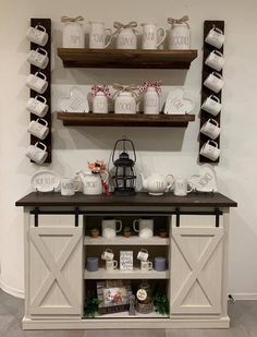 a table topped with lots of white dishes and mugs on top of wooden shelves