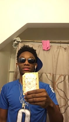 a man wearing sunglasses and headphones is holding a piece of food in front of his face