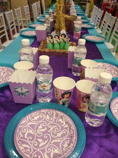 the table is set with purple and blue plates, water bottles, and napkins