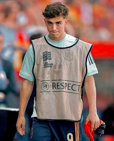 a young man is walking on the soccer field