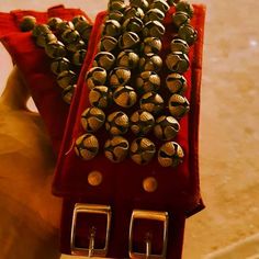 a red case filled with lots of metal beads on top of a table next to a hand