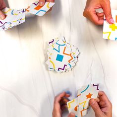 four people are holding cards with different designs on them and one person is pointing at it