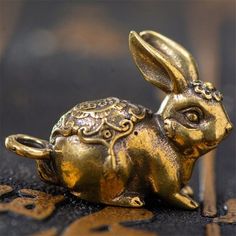 a golden rabbit figurine sitting on top of a black floor next to a wall