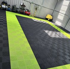 an indoor garage with green and black checkered flooring, two yellow cars in the background