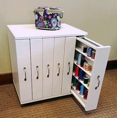 a white cabinet with two doors and several spools of thread