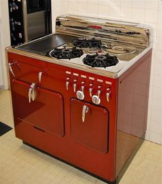 an old fashioned red stove with two burners on it's side in a kitchen