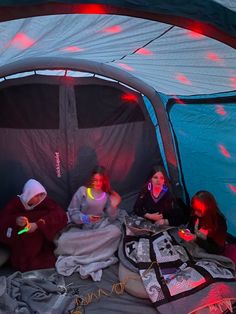 three people sitting in a tent with lights on