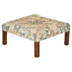 a footstool with a flower pattern on it's side and wooden legs