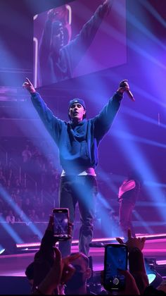 a man standing on top of a stage with his arms in the air and hands up