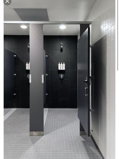 an empty bathroom with black and white tile on the walls, two urinals in the middle