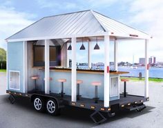 a small white building sitting in the middle of a parking lot next to a body of water