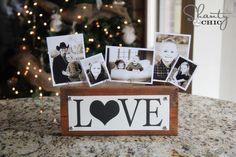 a wooden box filled with pictures sitting on top of a counter next to a christmas tree