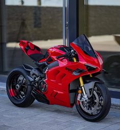 a red motorcycle is parked on the sidewalk