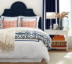 a bed with blue headboard and white comforter next to a window in a bedroom