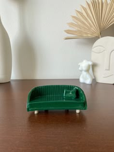 a green toy car sitting on top of a wooden table next to a white vase