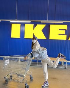 a woman in white jacket and jeans pushing a shopping cart with her feet up on it