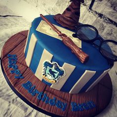 a harry potter birthday cake with glasses, wands and hat on the top tier