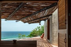 an open room with a view of the ocean and trees on the side, along with a wooden deck