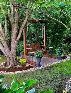 a wooden bench sitting under a tree next to a lush green forest